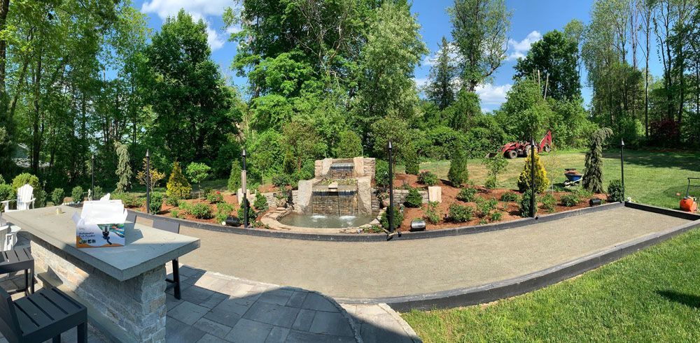 A panoramic view of a backyard with a waterfall and trees