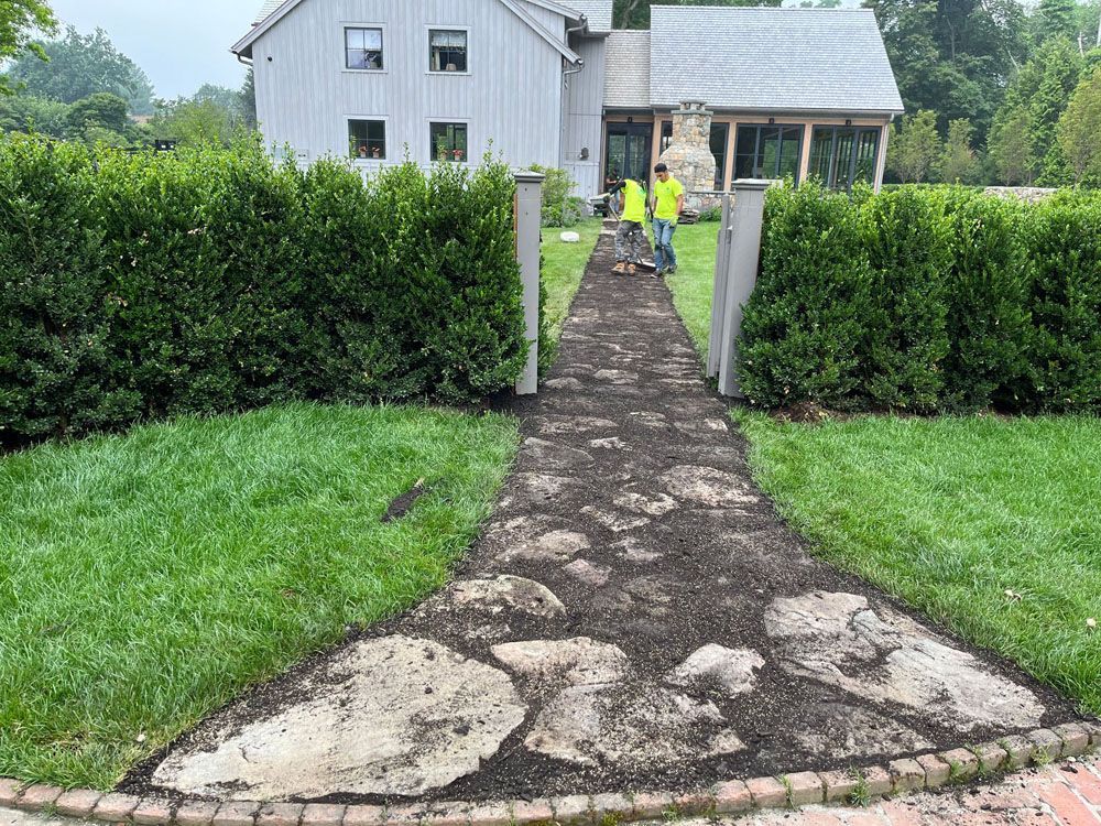A stone walkway leading to a house in a yard