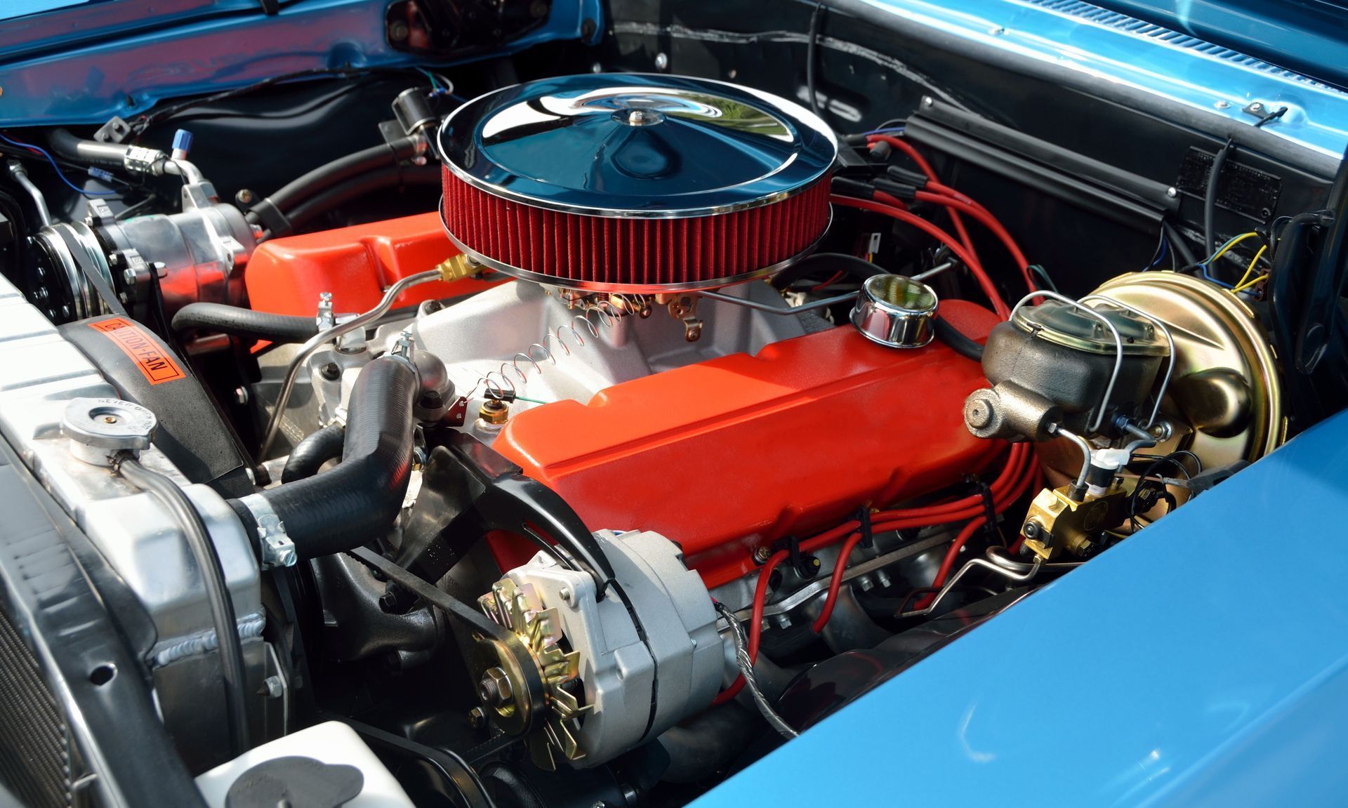 Blue car engine, red components, chrome air filter, black hoses and wires.