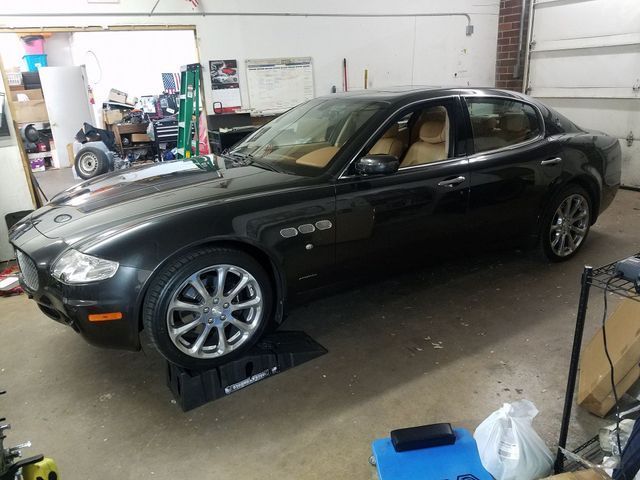 Black Maserati sedan on ramps in a garage with tan interior.