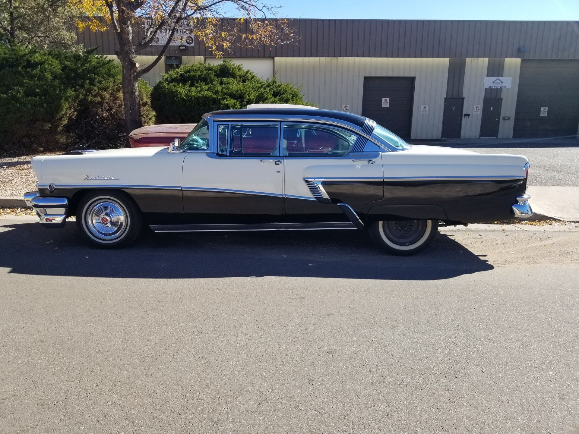 White and black classic car parked on the side of a road, with chrome details.