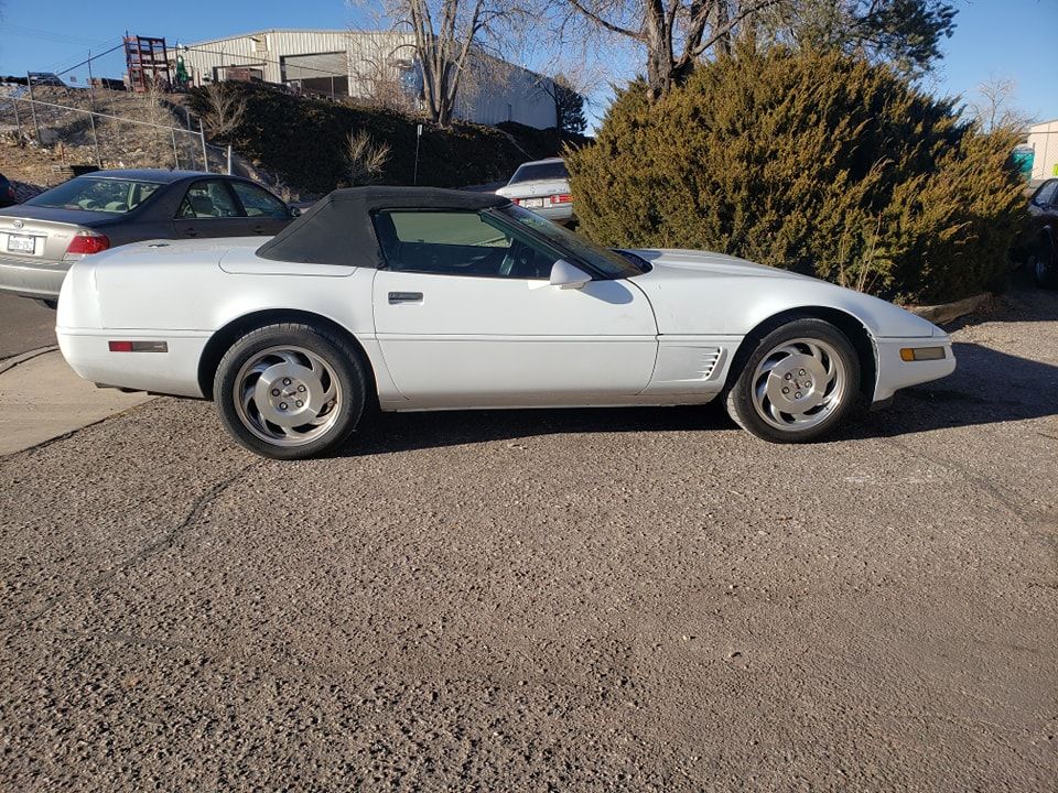 White convertible Chevrolet Corvette parked outside on a sunny day.