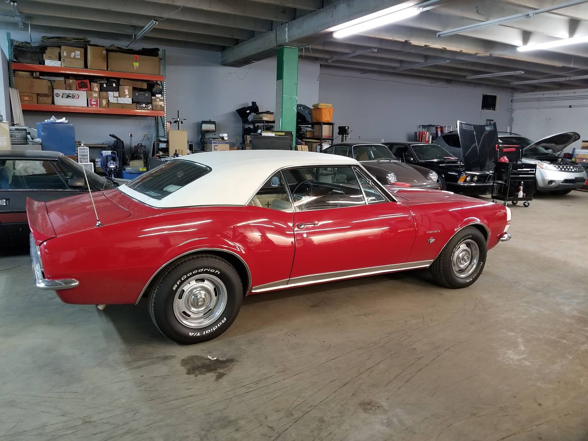 Red classic car with white top in a garage.