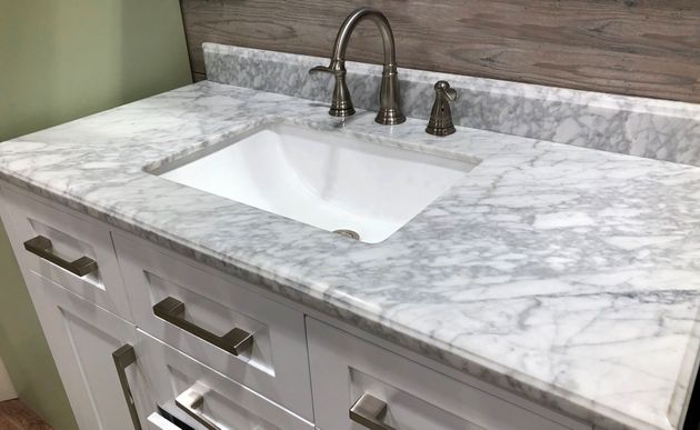 White marble bathroom vanity with undermount sink and brushed metal faucet, seen at an angle