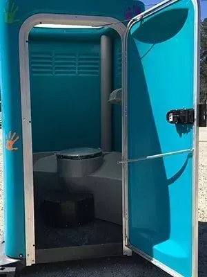 Turquoise portable toilet with the door open, showing the interior.