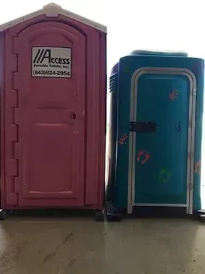 Pink and blue portable toilets side by side on a floor, with the pink one labeled 
