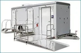 Portable medical isolation unit with metal ramps and railings, shown in white and gray.