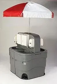 Portable red-and-white umbrella over a gray cooler with small white electronics attached