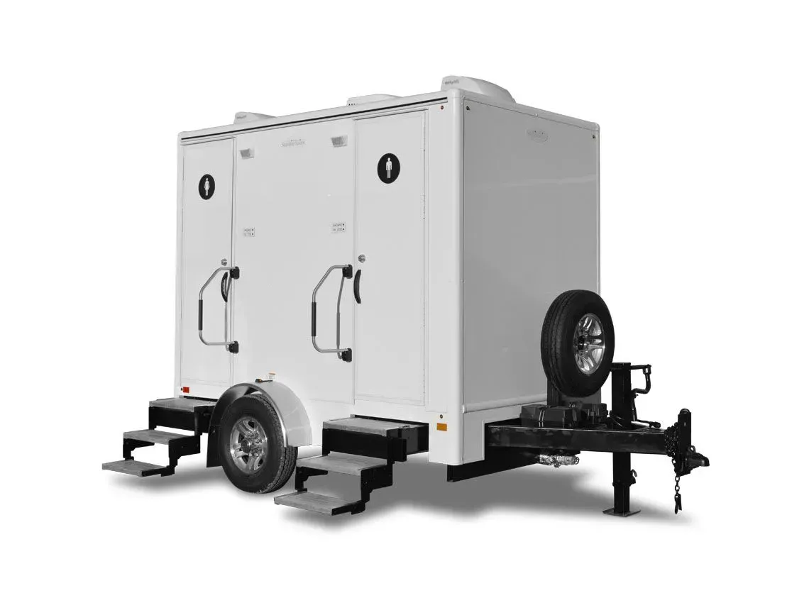 White mobile trailer with double doors, steps, and a spare tire on a black chassis.