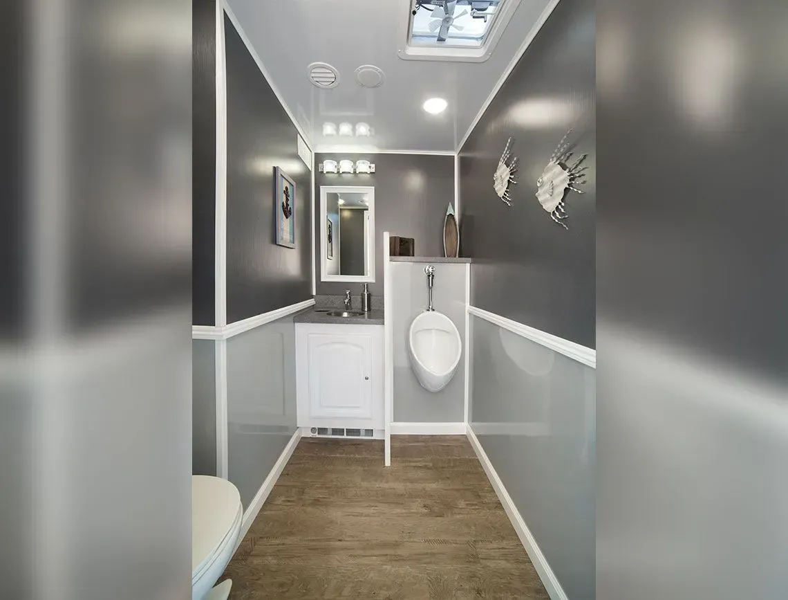 Narrow gray-and-white hallway with wood floor, ceiling lights, and a small bathroom sink at the end