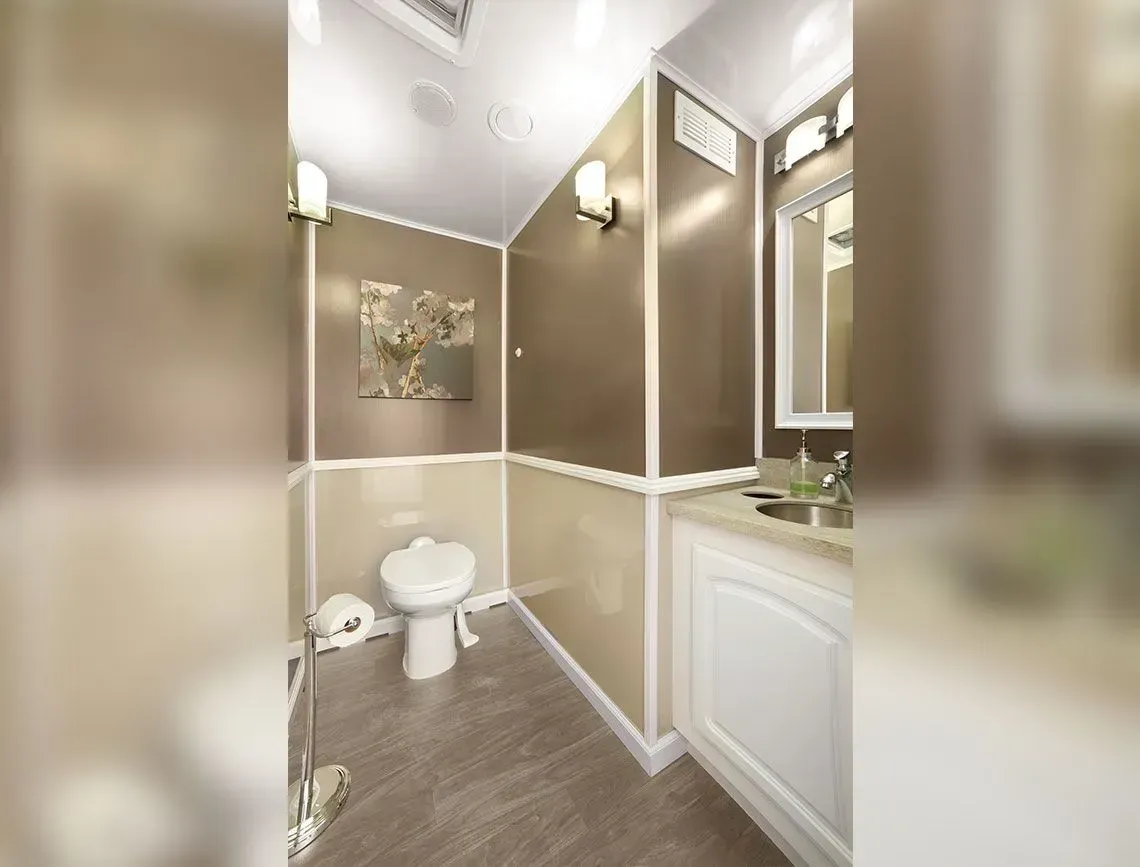 Small beige bathroom with toilet, vanity sink, and wall sconce lighting.