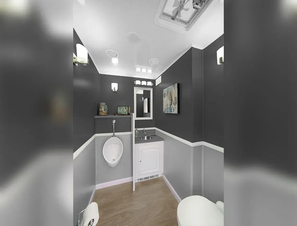 Modern restroom with gray walls, wood-look floor, white sink, and mirror under bright ceiling lights
