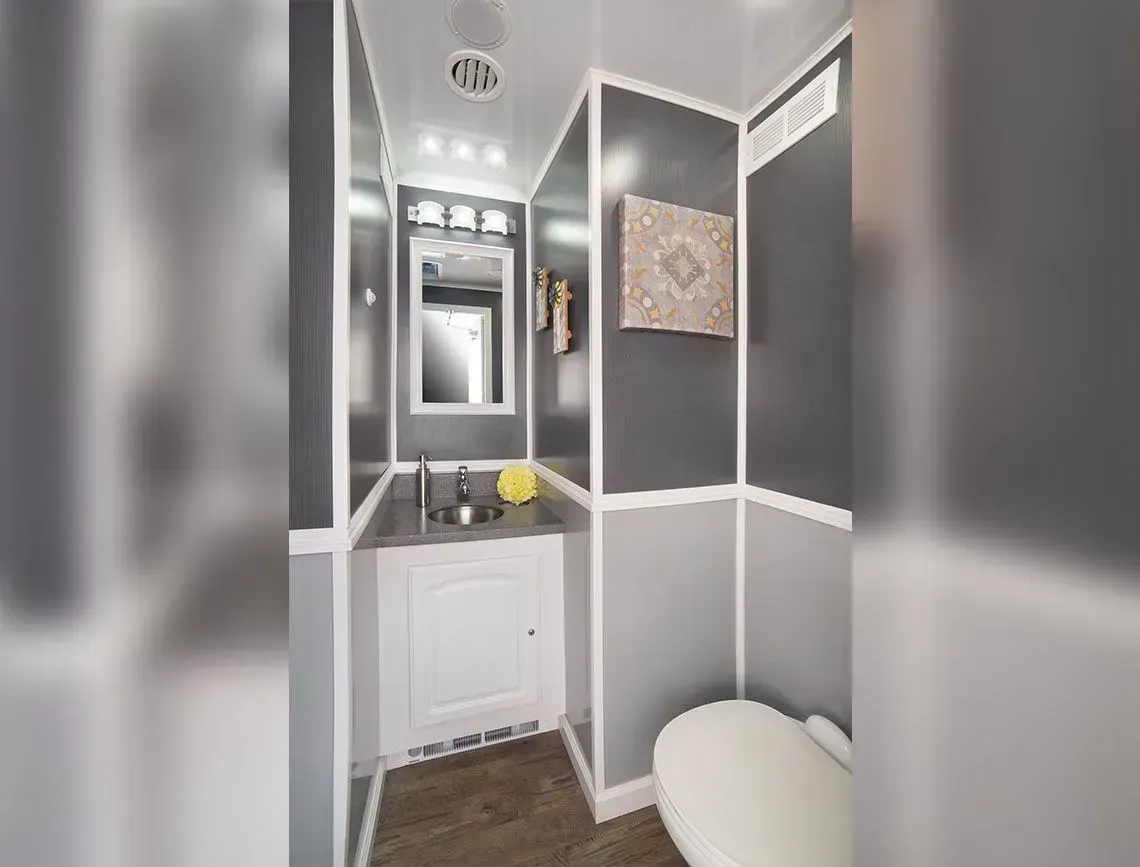 Narrow modern bathroom with gray walls, white vanity, mirror, and toilet