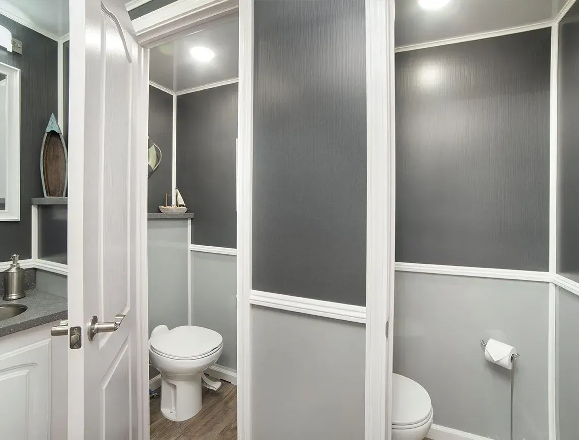 Small gray-and-white bathroom with toilet, sink, and stall-like panels
