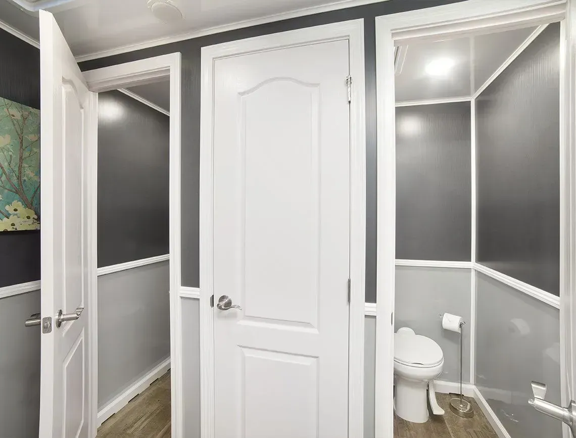 Small bathroom with gray walls, white trim, and a toilet beside a walk-in shower.