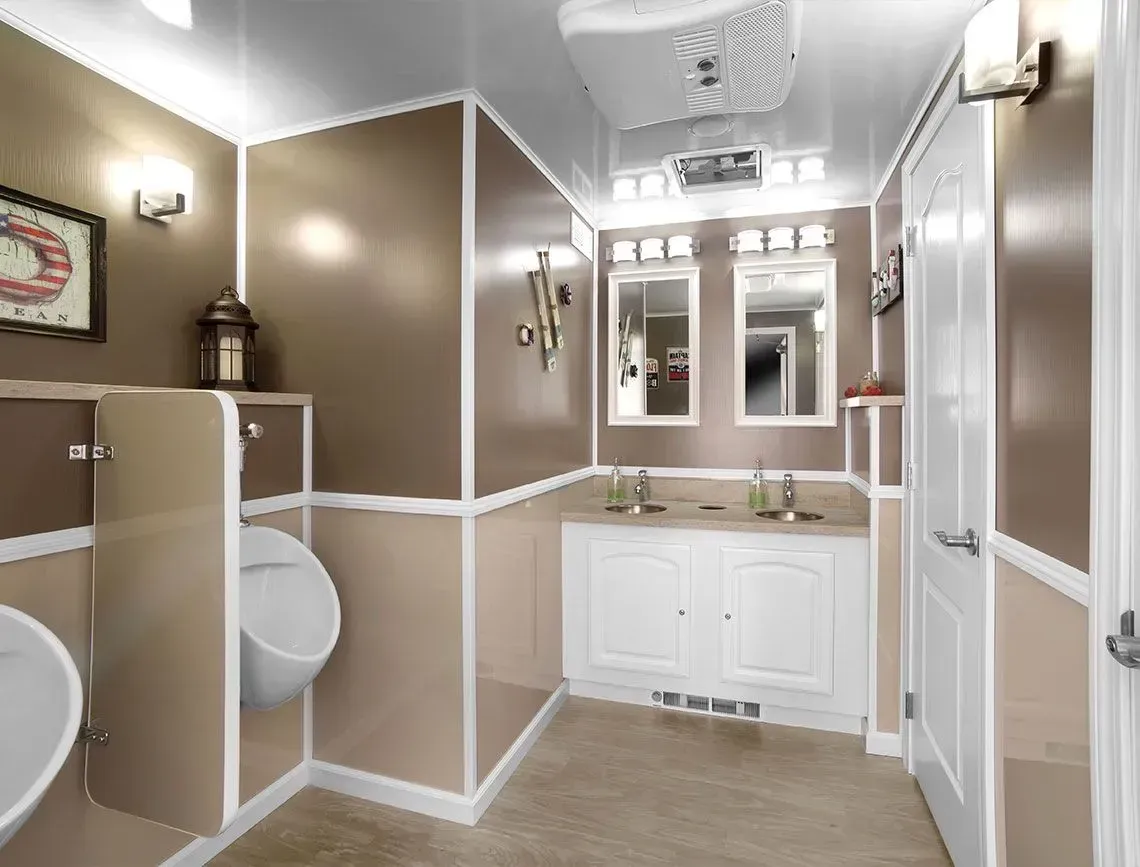Accessible public restroom with beige walls, white trim, sinks, mirrors, and toilet stalls