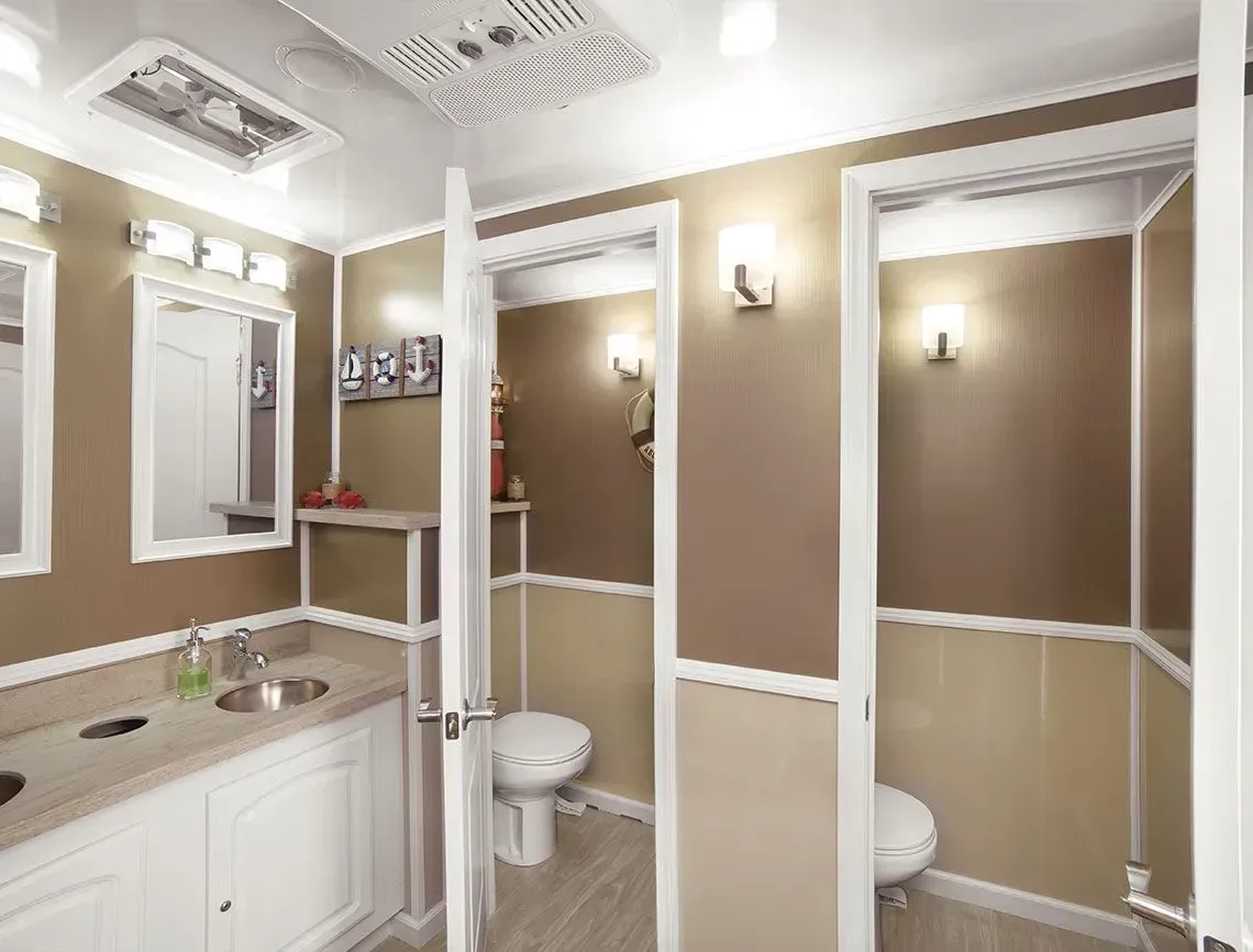 Bright bathroom interior with vanity, mirrors, toilet, and beige walls with white trim