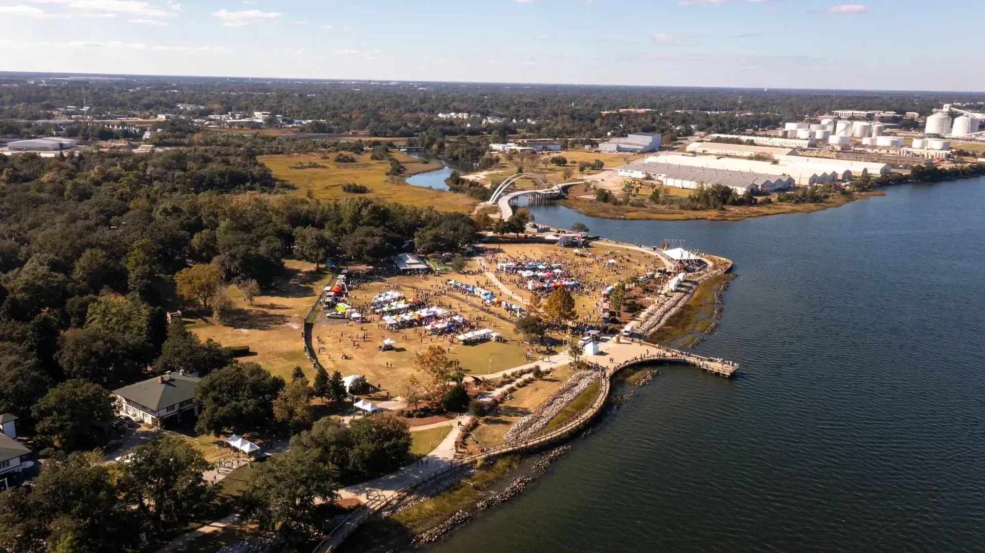 Aerial view of a lakeside park with tents, trees, and buildings along the shore