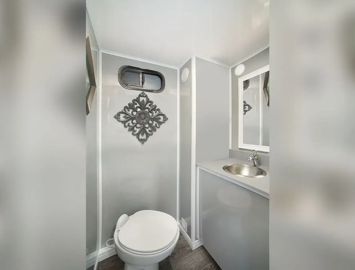 Small bathroom with toilet, sink, mirror, and gray walls.