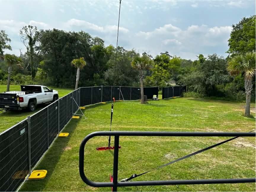 Fenced grassy field with a white pickup truck and trees under a bright sky