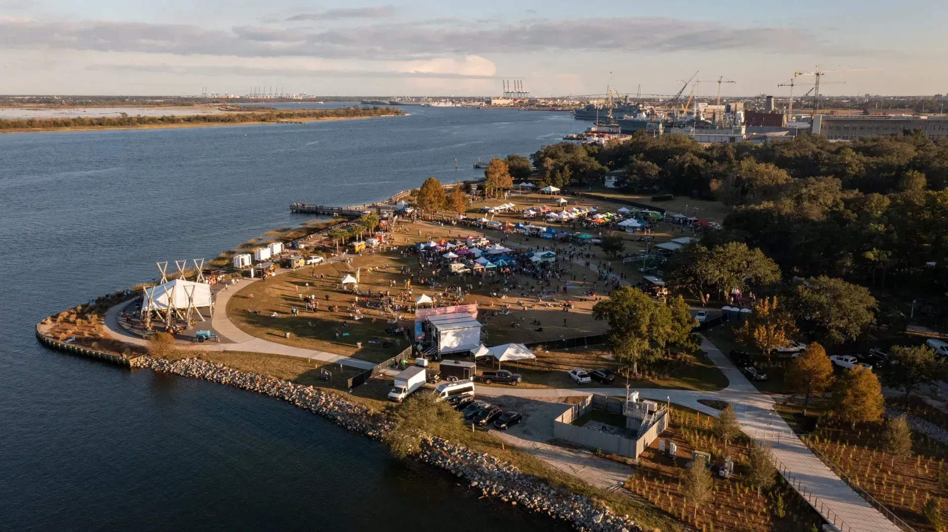 Aerial view of a rocky waterfront park with paths, trees, boats, and water under a clear sky