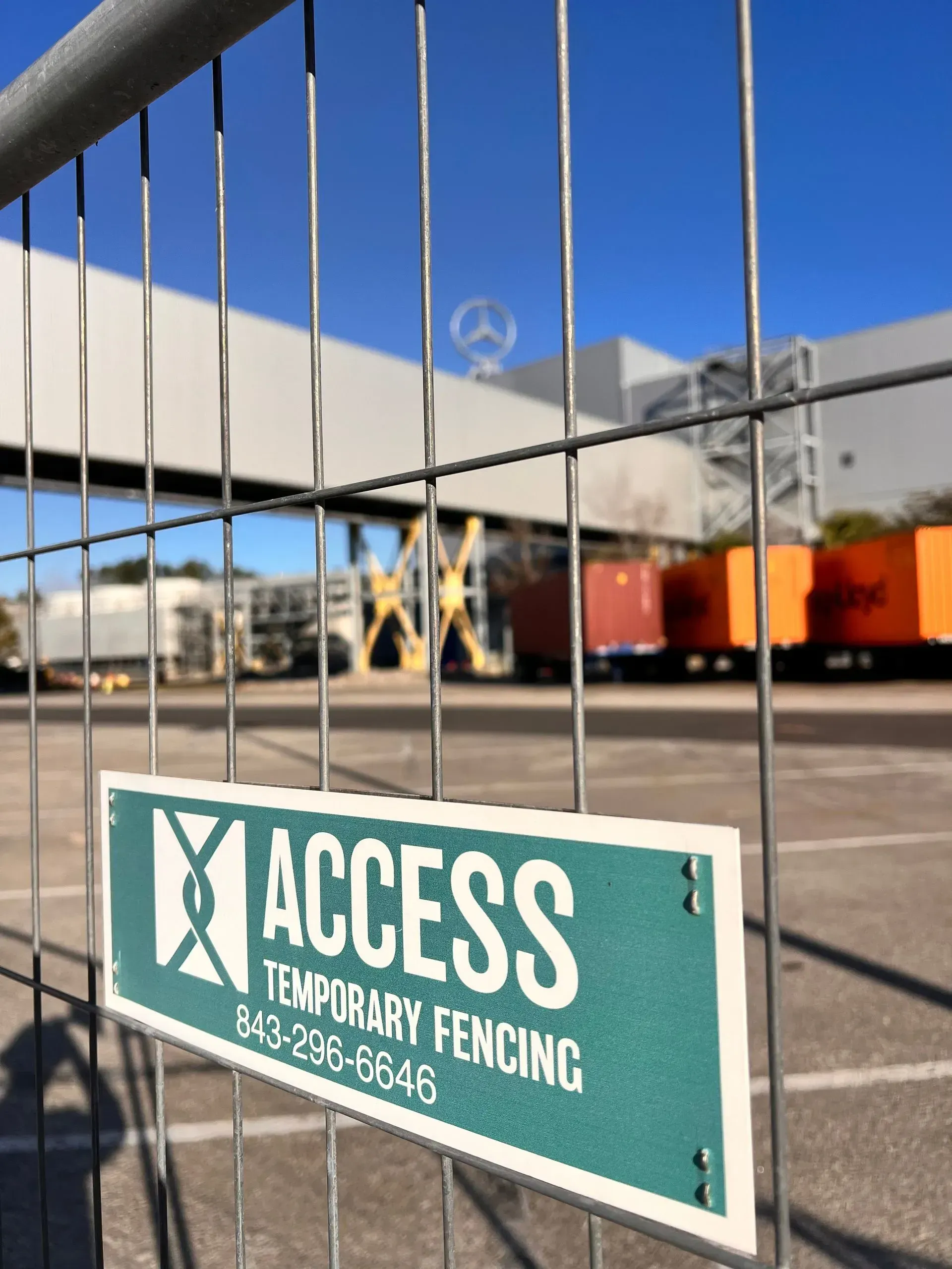Green “ACCESS Temporary Fencing” sign on a metal fence at a construction site.