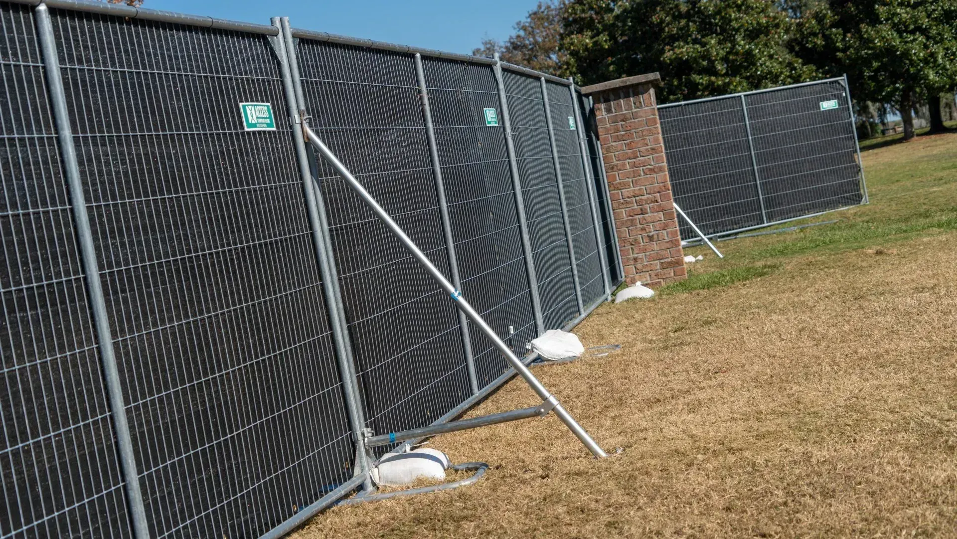 Solar panel arrays behind chain-link fencing along a grassy field on a sunny day