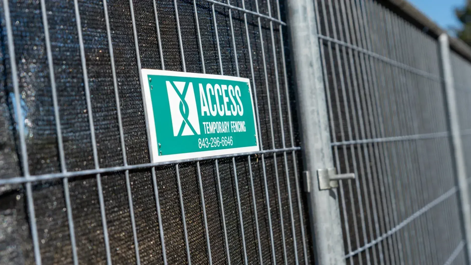 Green access sign on a wire fence beside a closed gate.