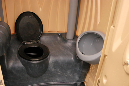 A black toilet with the lid open in a beige restroom stall, next to a gray urinal.