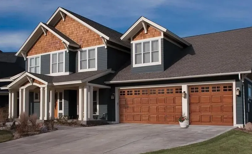 Blue house with brown garage doors, wood accents, and concrete driveway.