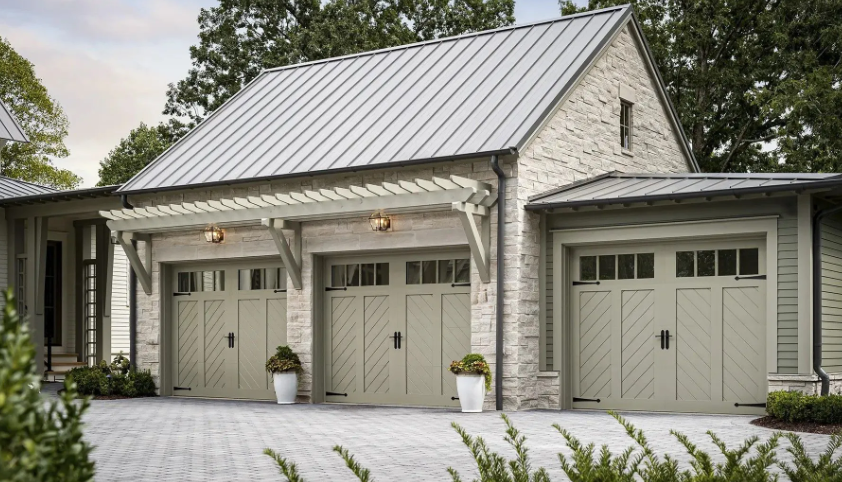 Three-car garage with light green doors and stone facade under a gray metal roof.