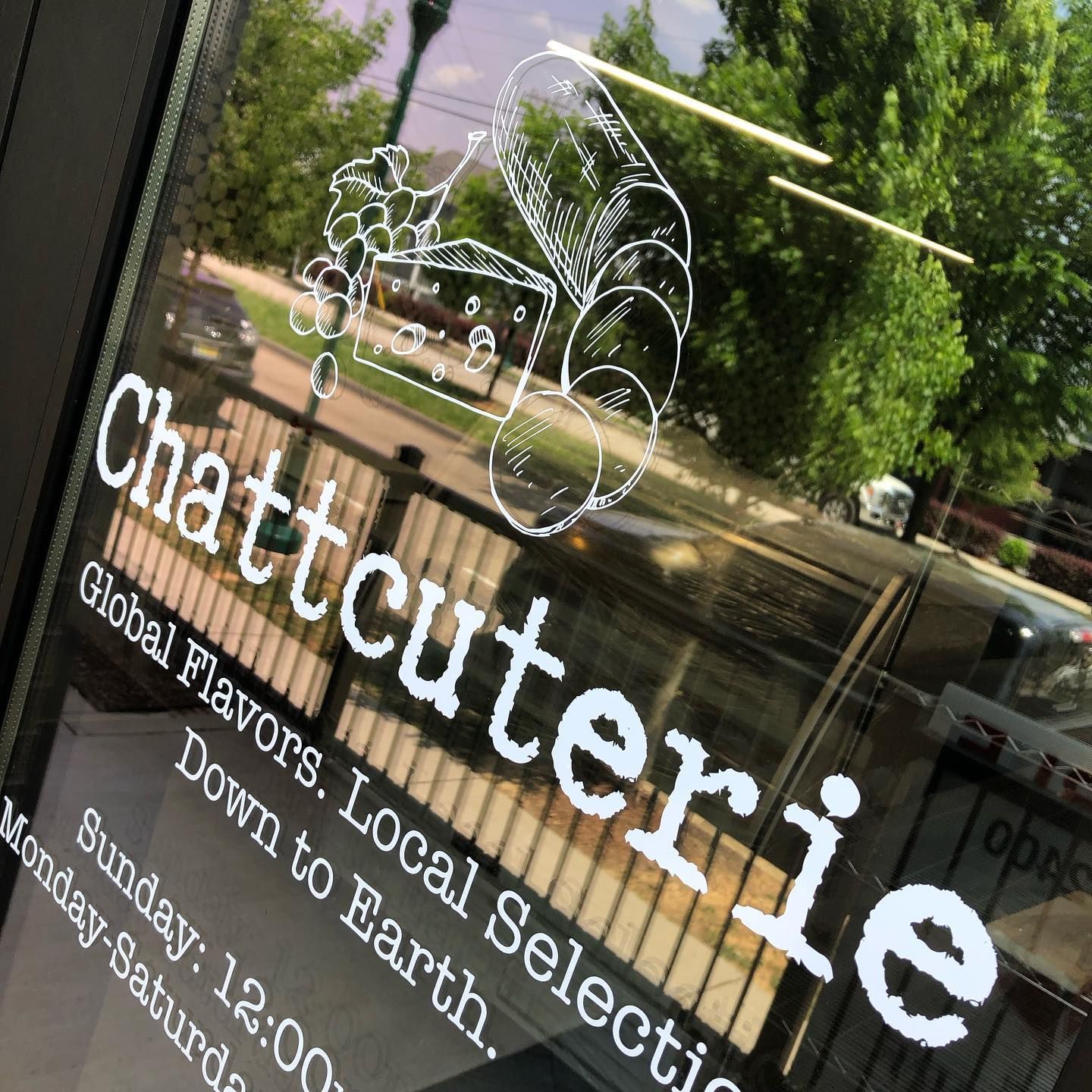 Chattcuterie storefront window with logo and hours. 