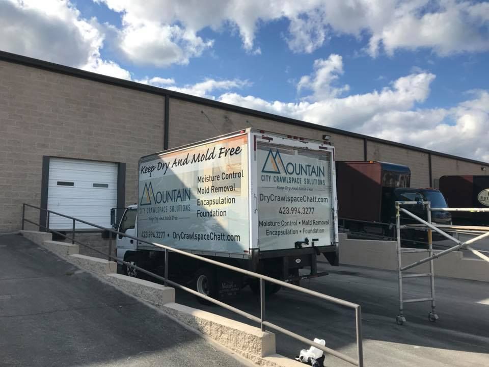Truck at loading dock, white box truck with blue logo on side.