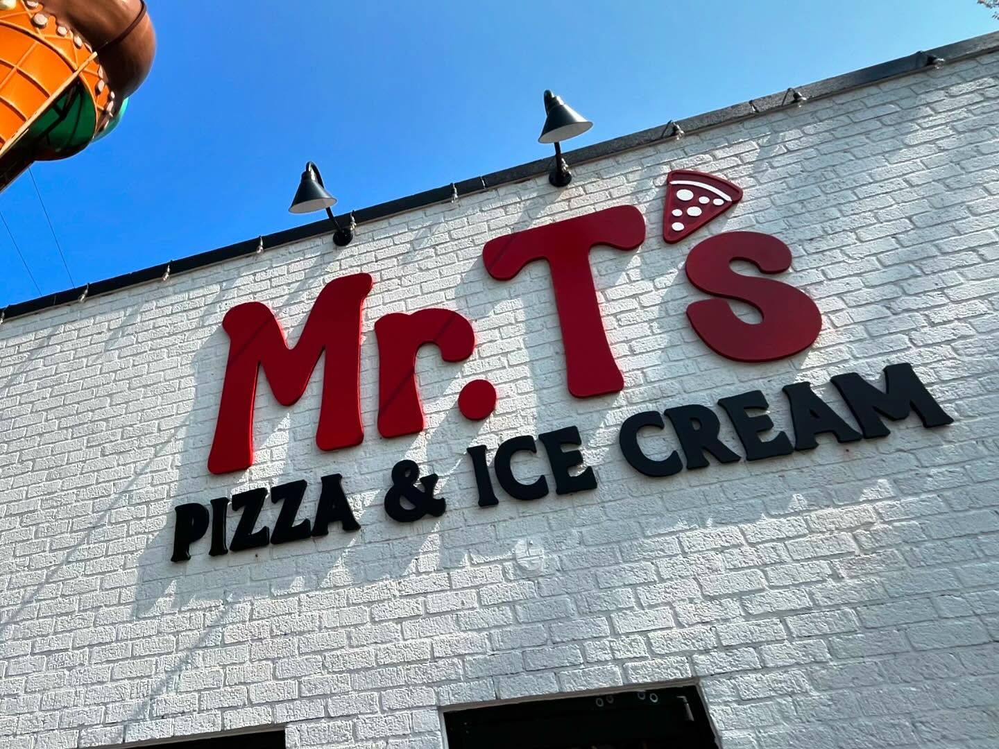 Mr. T's Pizza & Ice Cream sign on white brick building with a blue sky above.