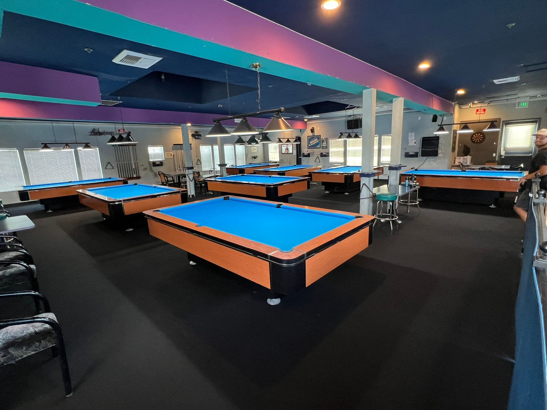 Pool hall with blue-felt tables and overhead lights in a spacious, colorful room