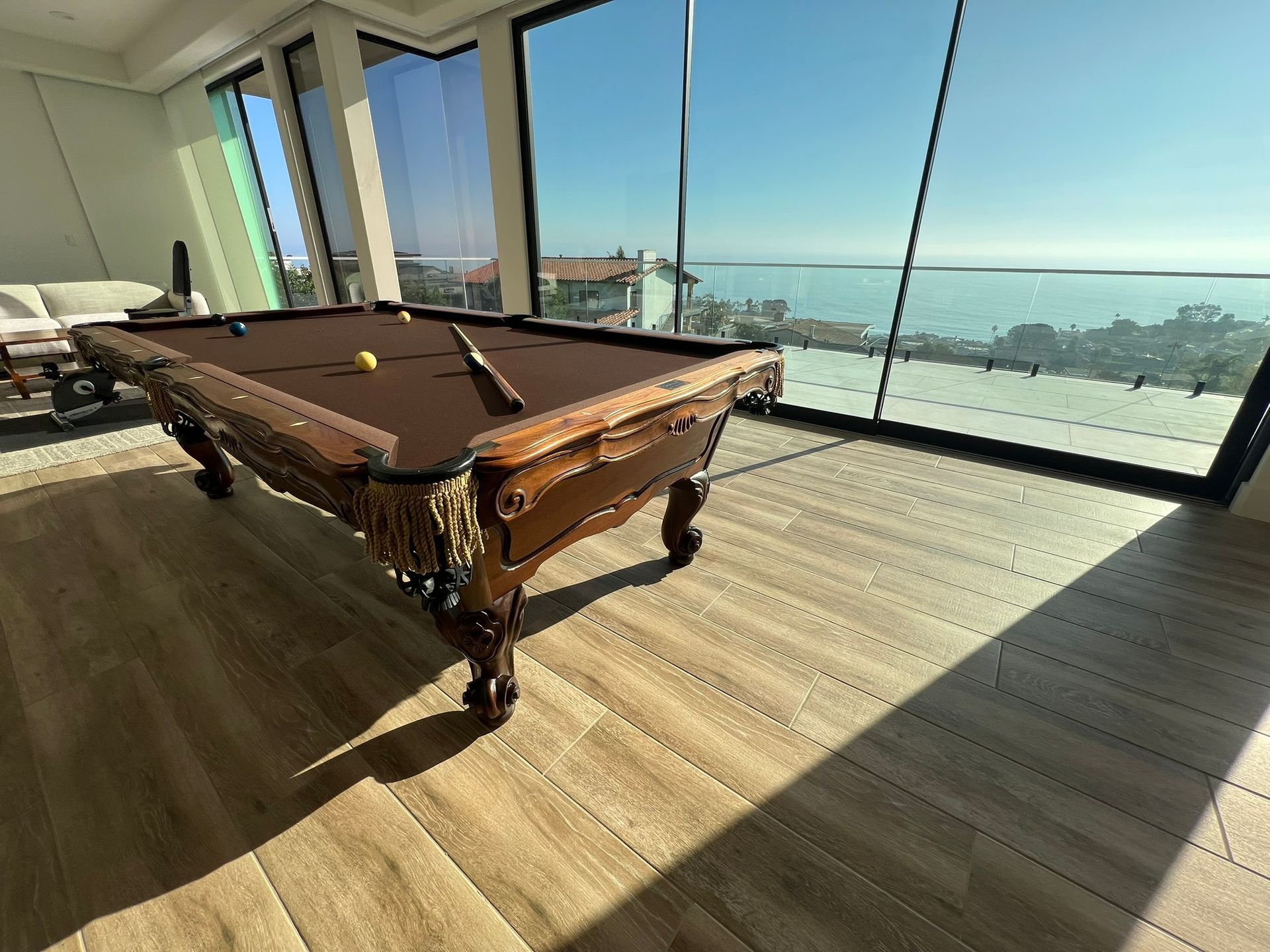 Pool table in a bright room with floor-to-ceiling windows overlooking the ocean