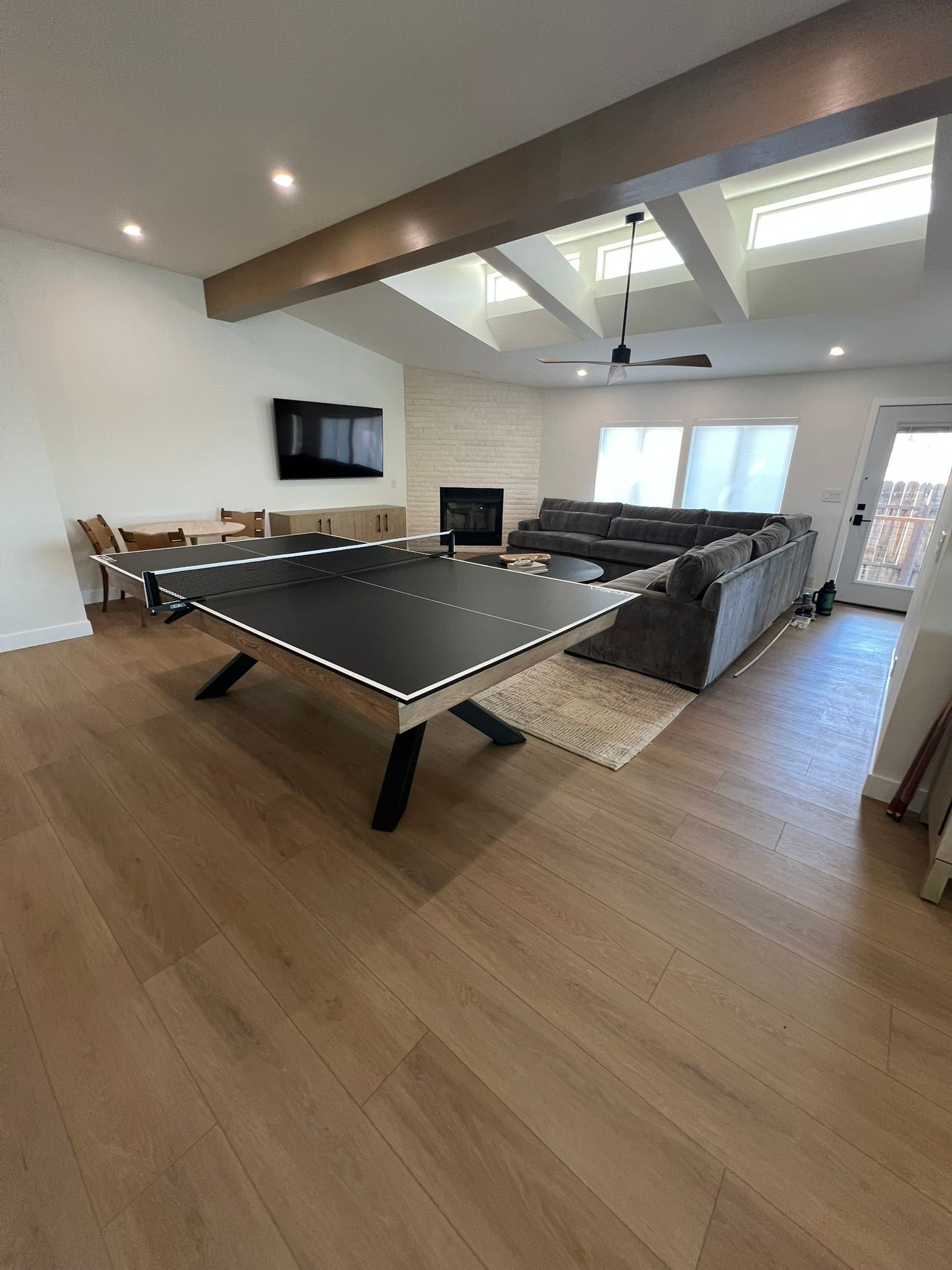 Bright game room with pool table, sectional sofa, TV, and skylights