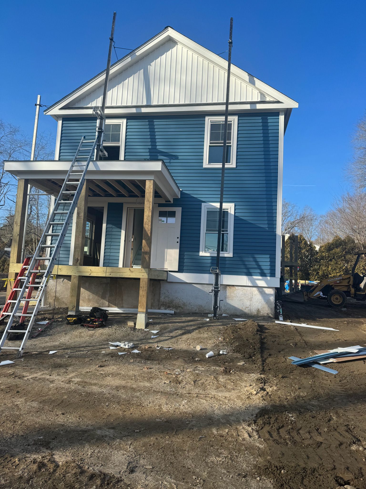 A blue house is being remodeled with a ladder on the side of it