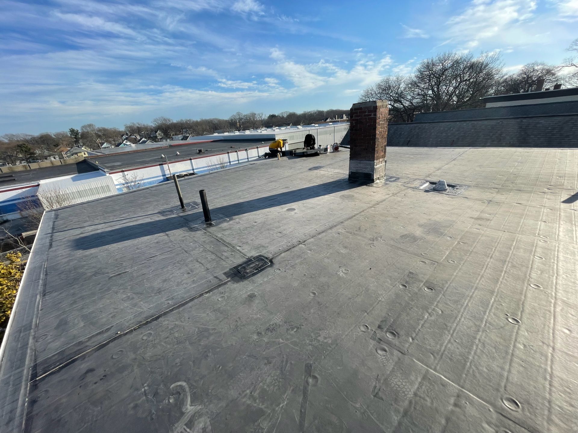 A roof with a chimney on it and a blue sky in the background