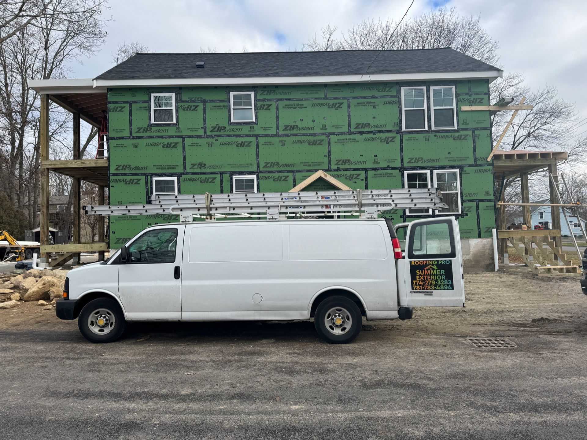 A white van is parked in front of a house under construction
