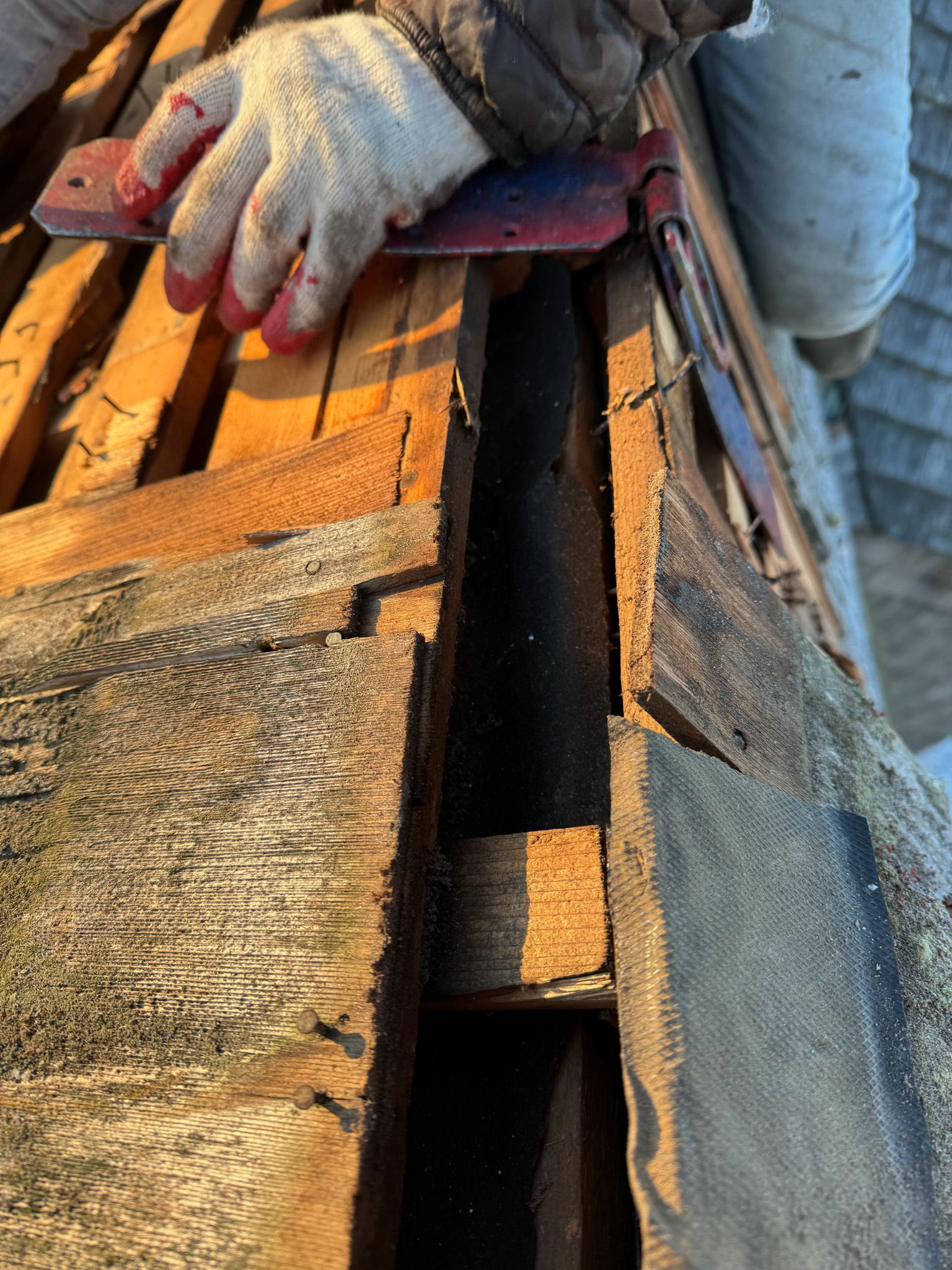 A person wearing gloves is cutting a piece of wood