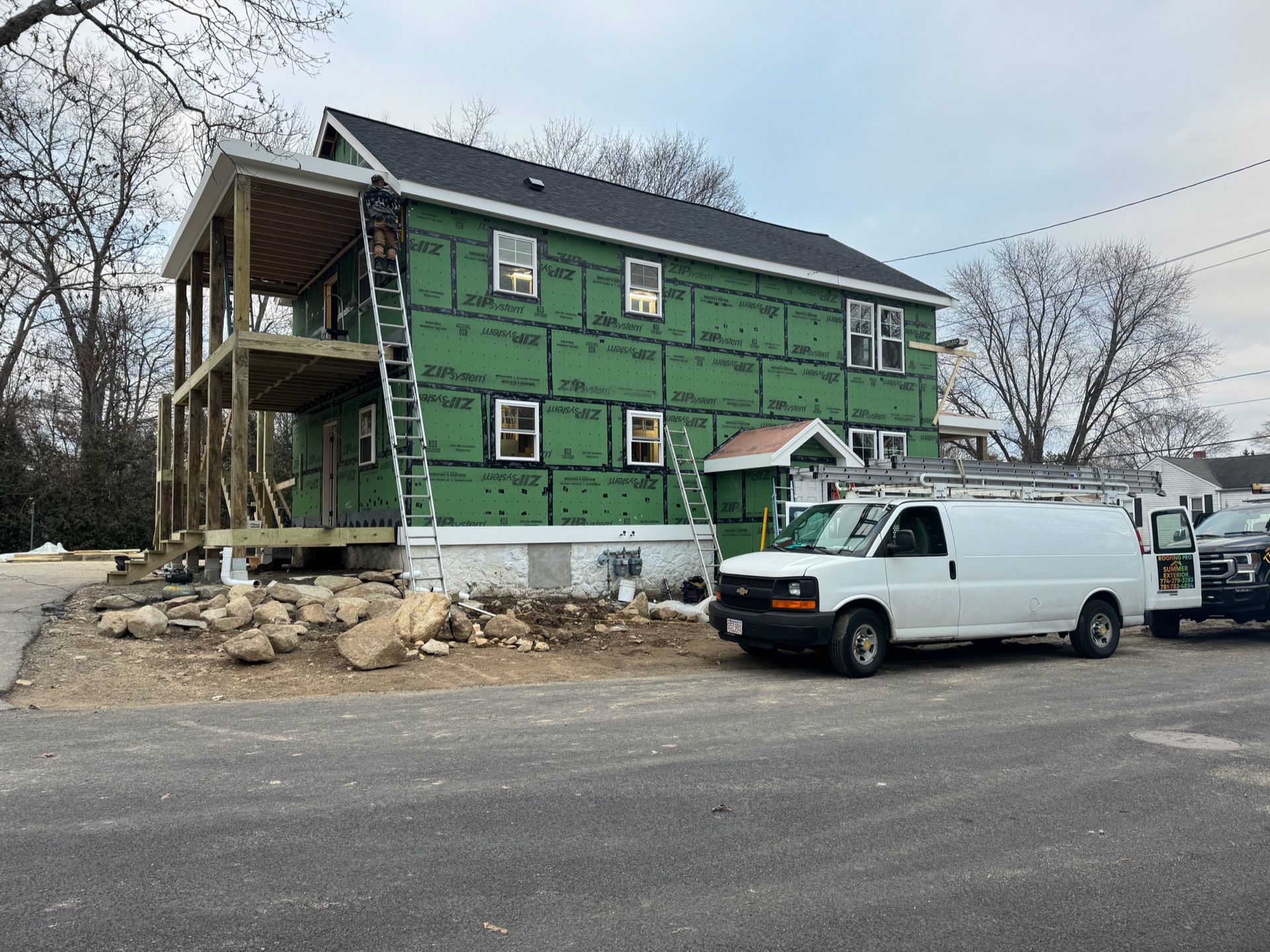 A white van is parked in front of a house under construction