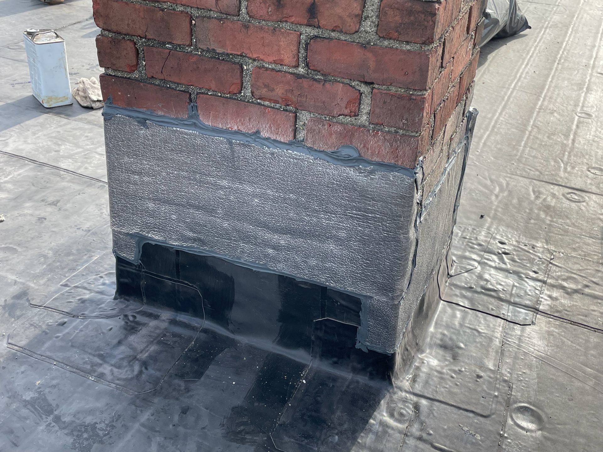 A brick chimney is being repaired on a roof