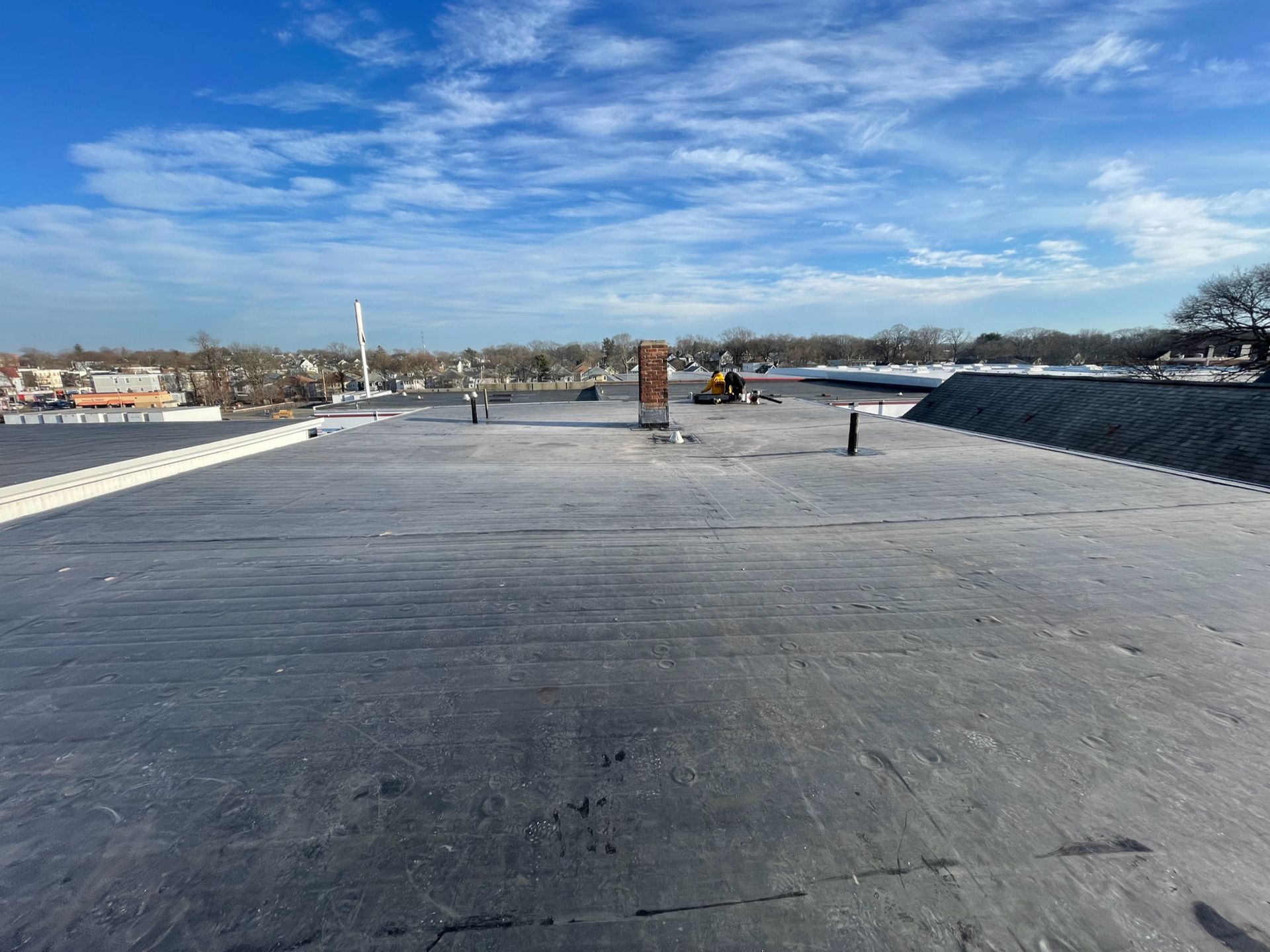 A roof with a chimney on it and a blue sky in the background