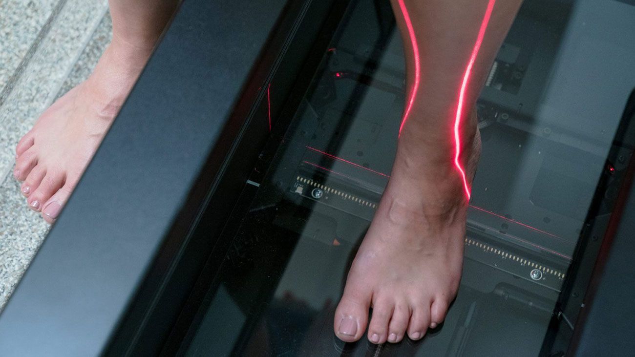 A person's foot is being scanned by a machine with a red light coming out of it