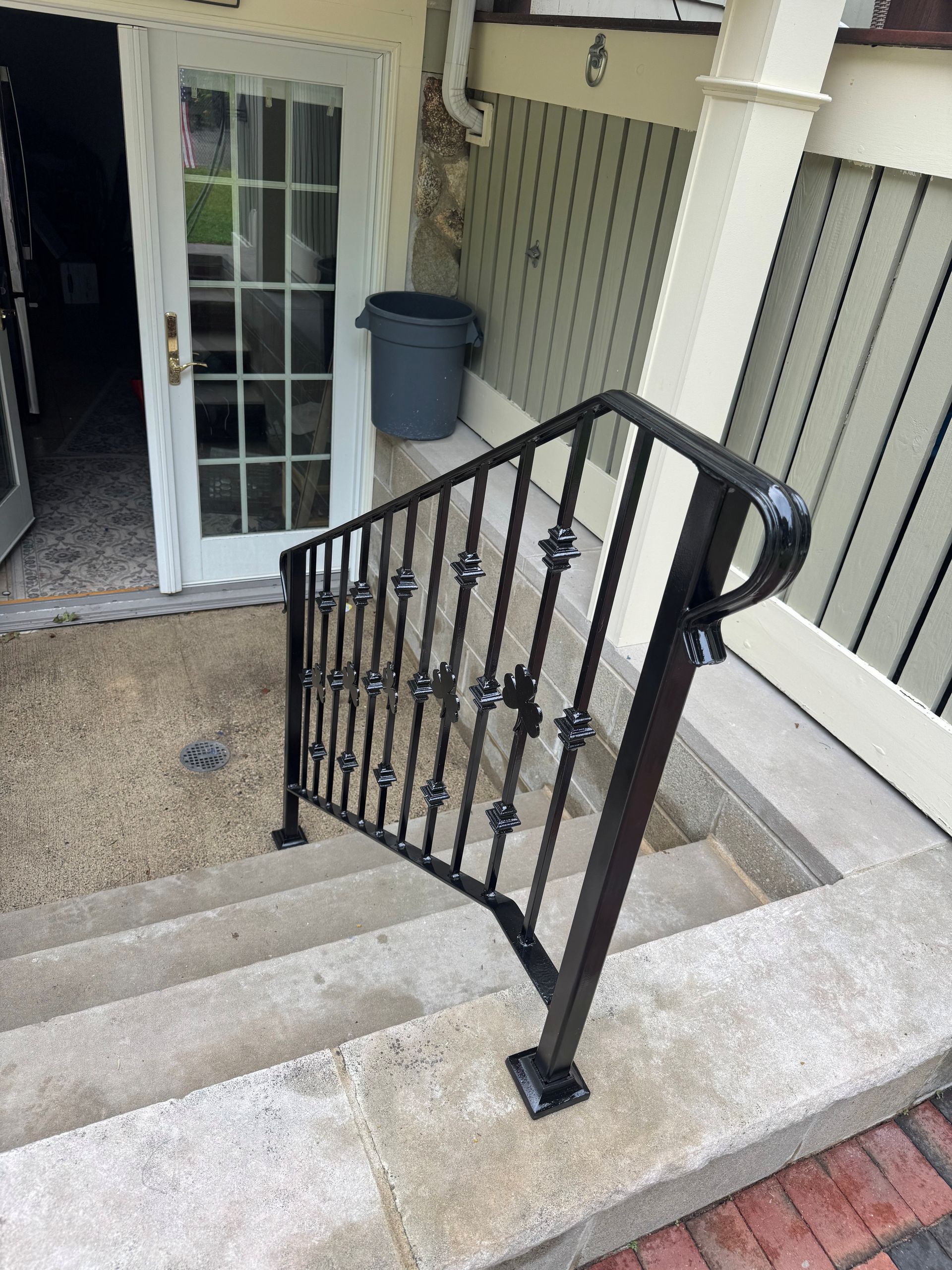 Stairway landing with black metal railing, concrete steps, and a glass door entrance.