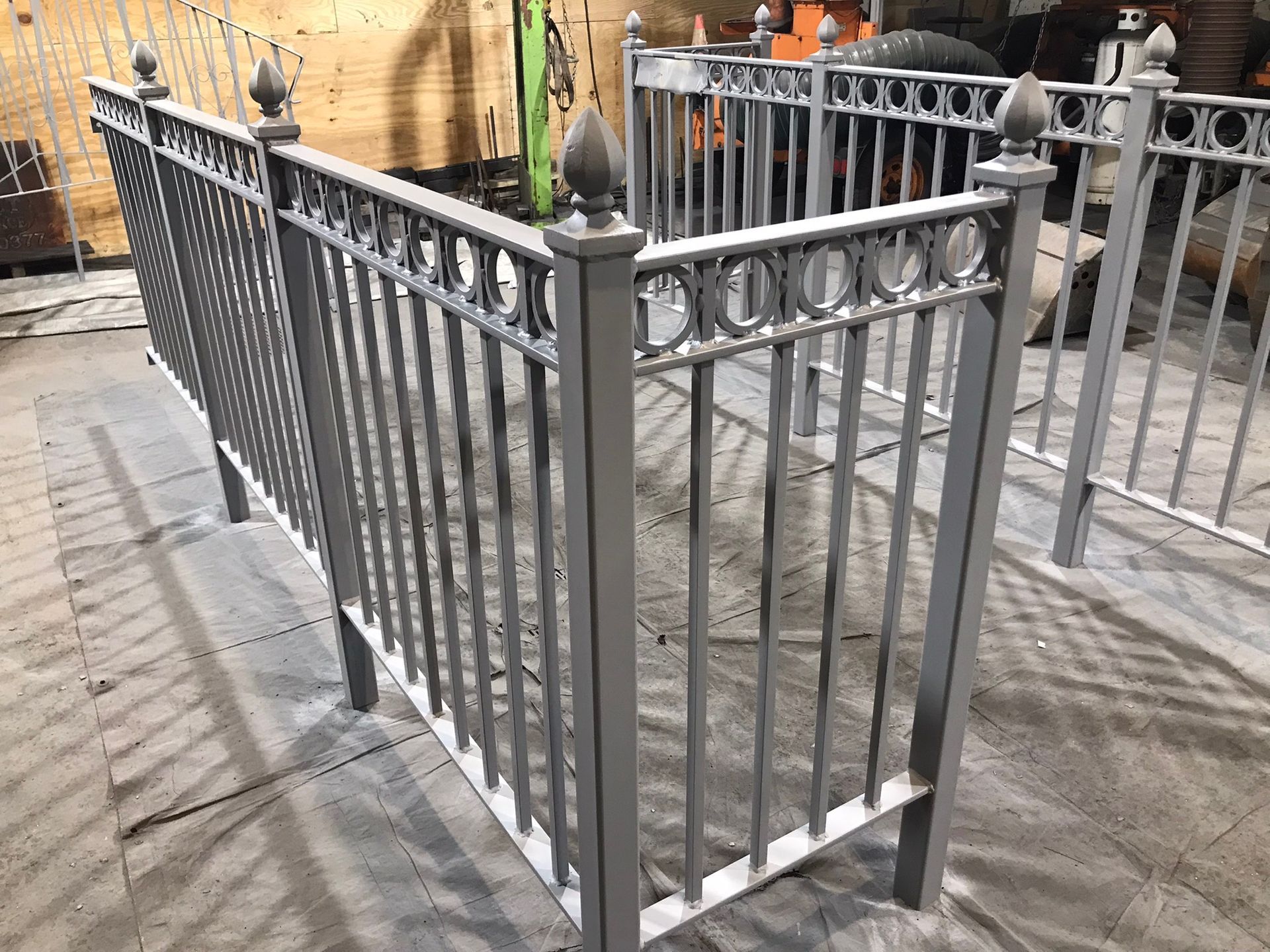 Gray metal fence enclosing a small outdoor platform beside a stone-paved walkway