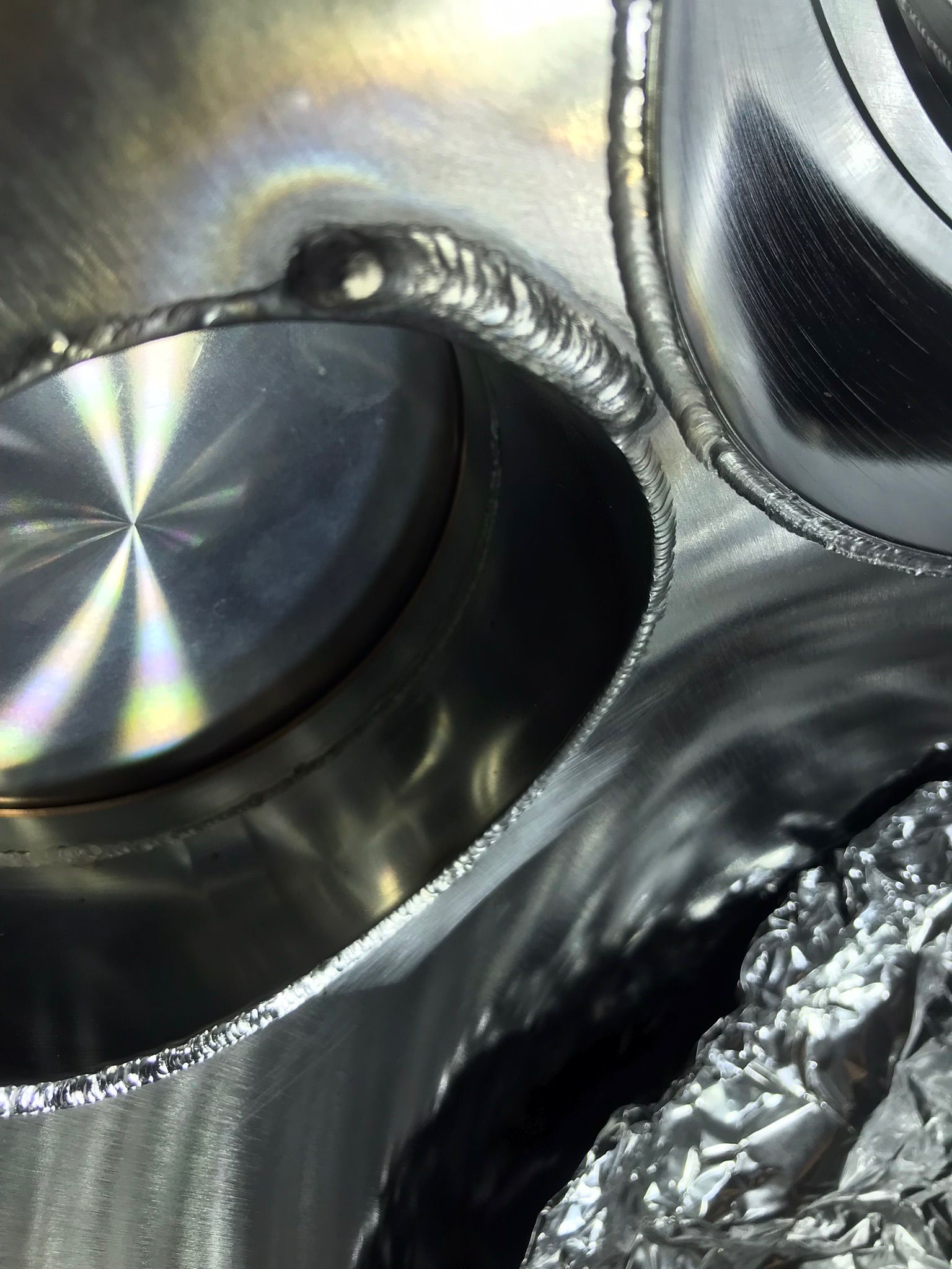 Close-up of a shiny metal container interior with circular reflective surfaces and crumpled foil.