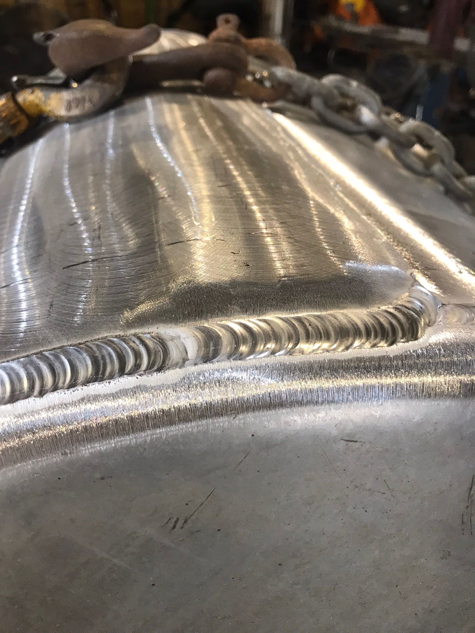 Close-up of a welded metal surface with visible bead seams and reflections