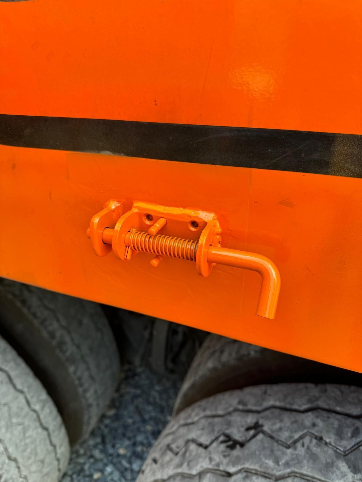 Orange vehicle panel with a small spring latch near the wheel well